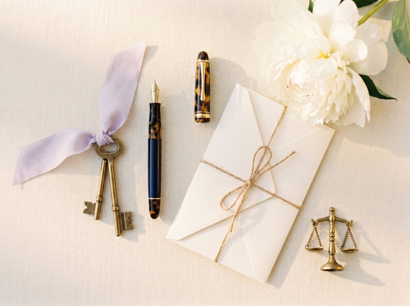 An elegant closing-day flat-lay with brass keys, fountain pen, and white peony